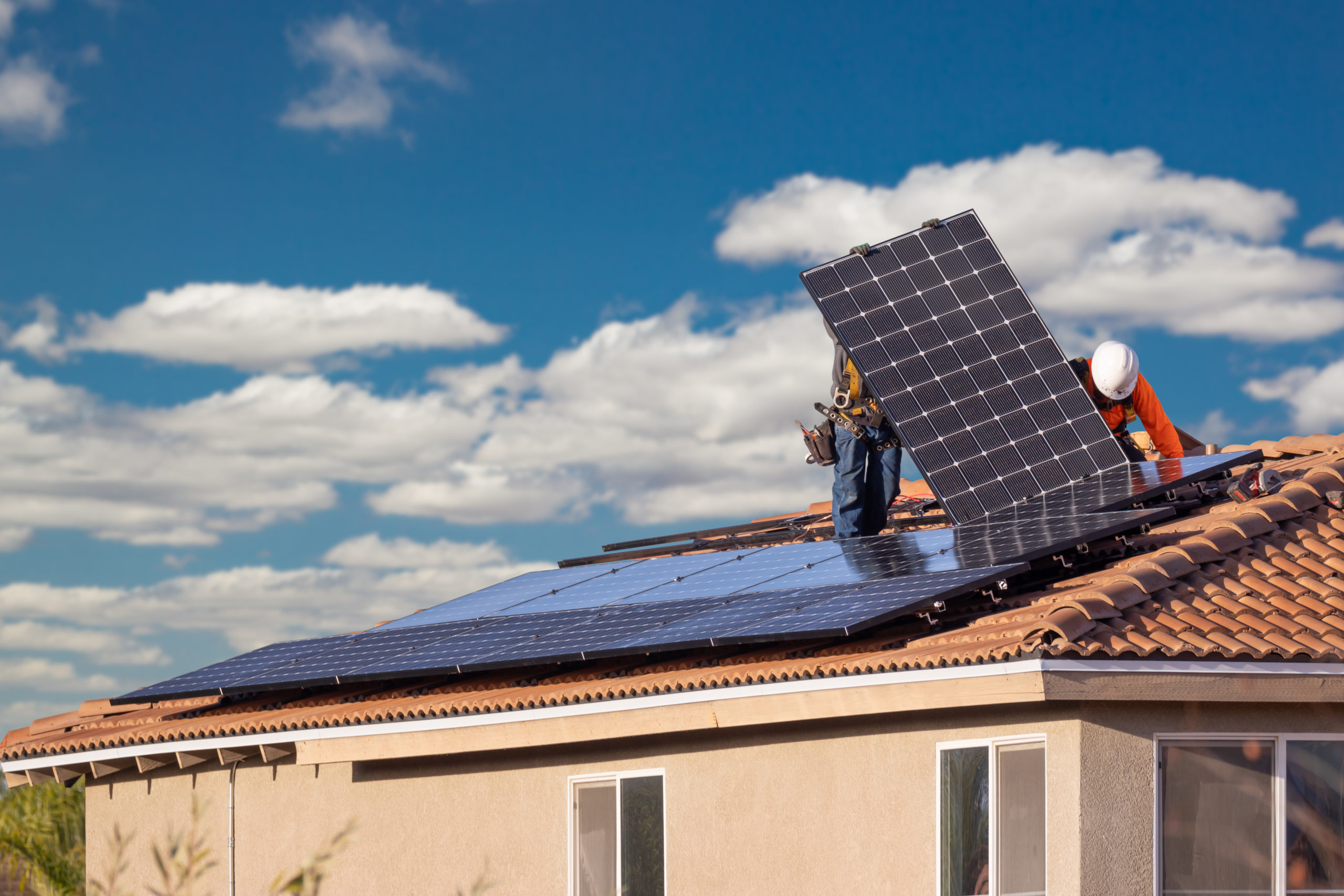 Men at work installing solar panels on a roof
