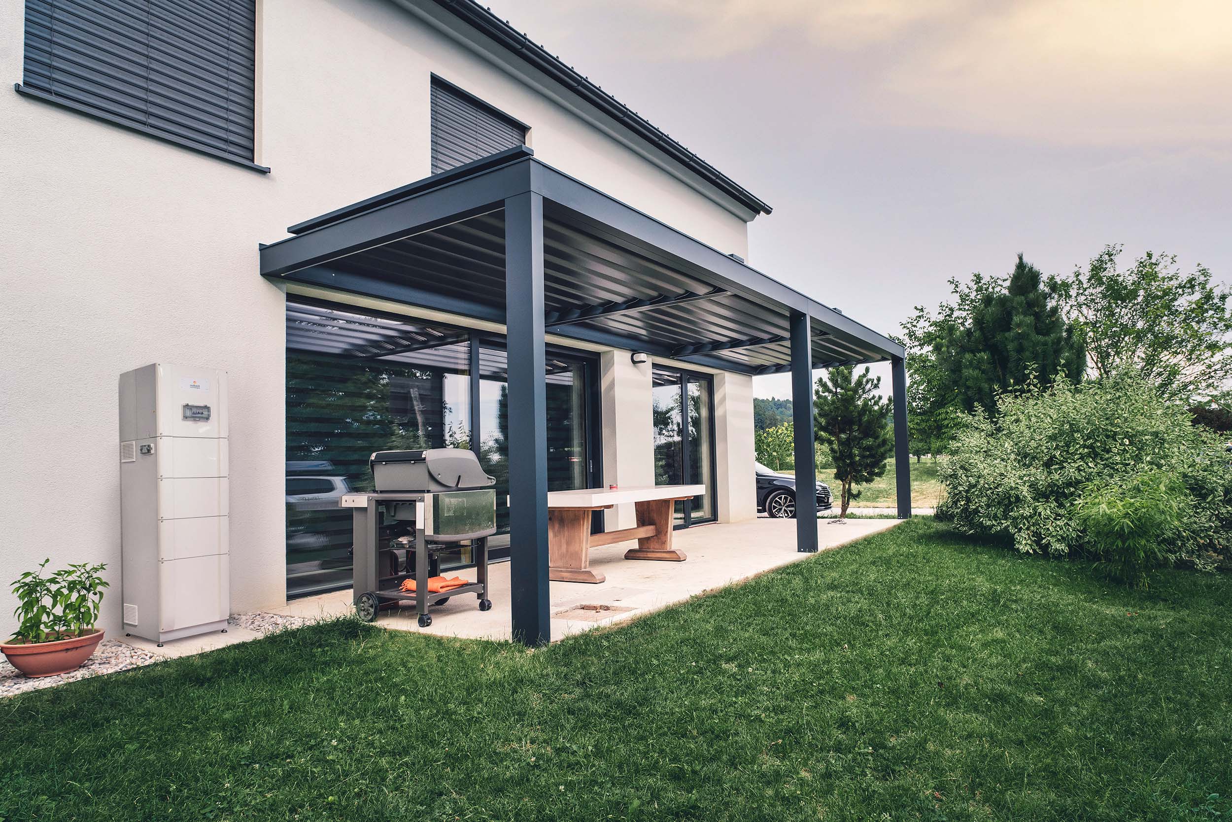 Smart Battery Installed on the Side of a lush green house with pergola