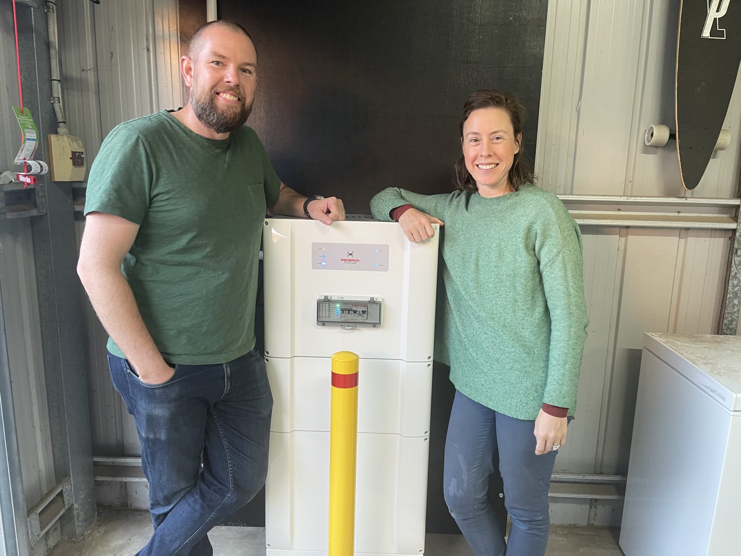 Image showing 2 people standing next to their Redback Smart Battery in their garage