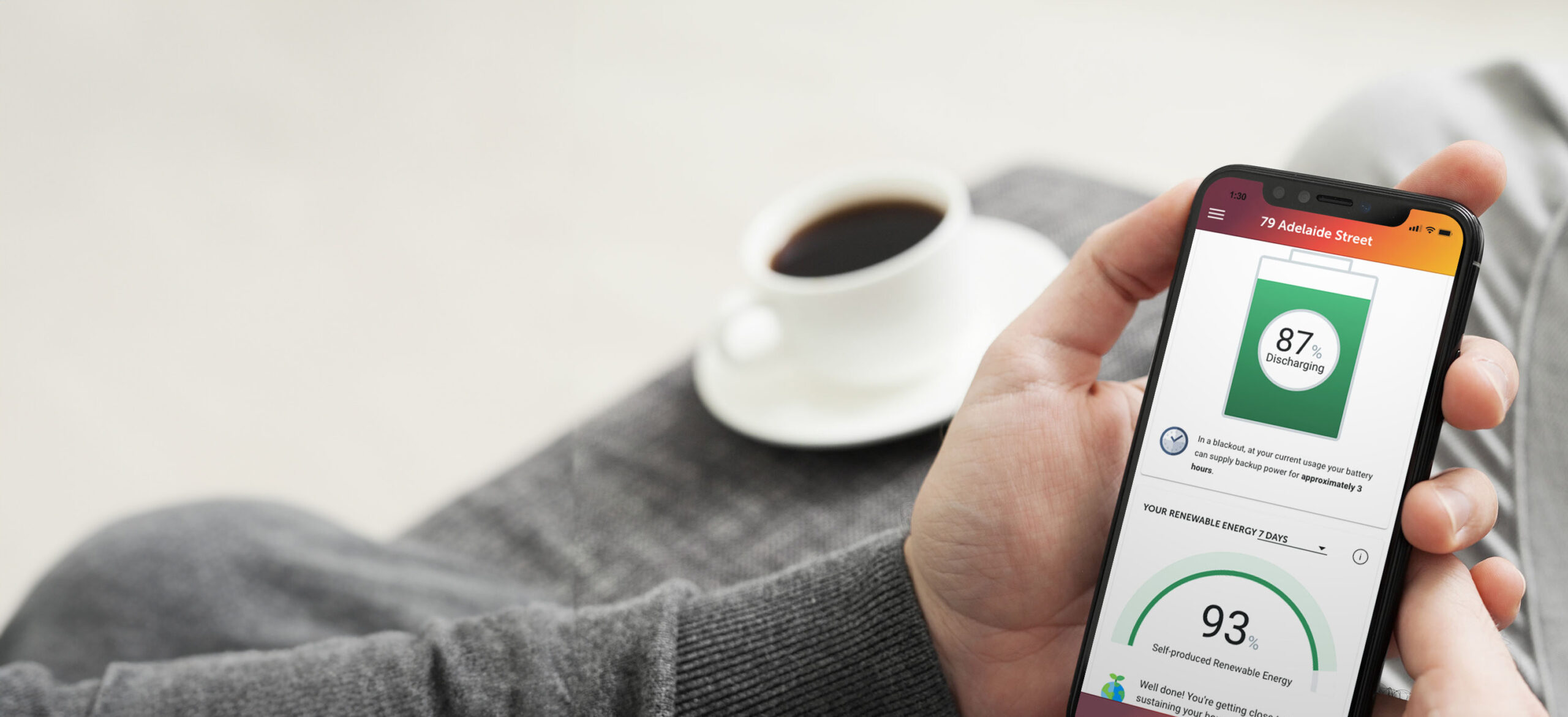 A screen from the Redback App on a phone in a persons hand with a coffee in the background